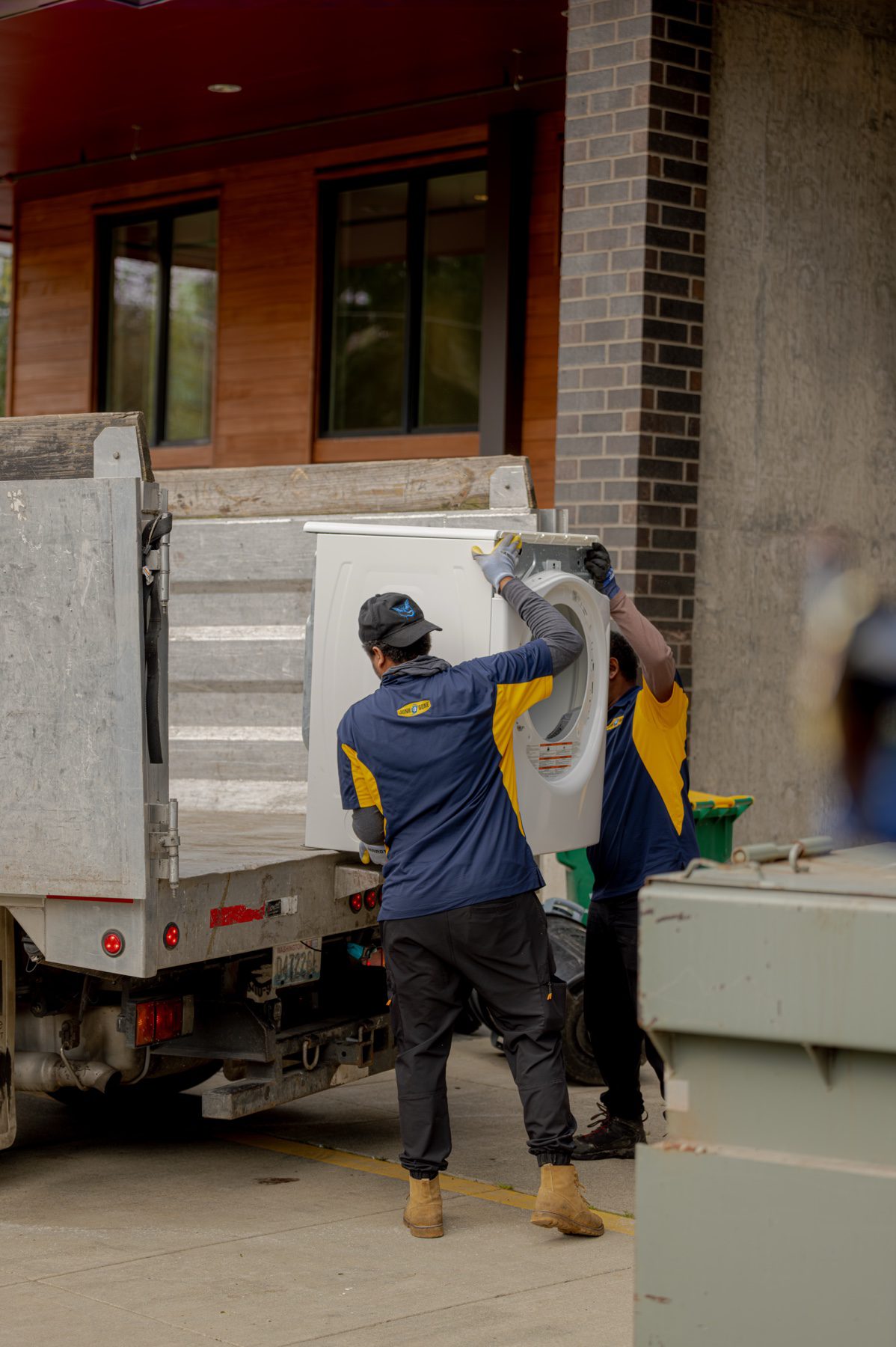 Appliance removal in Seattle - Junk B Gone crew lifting a washing machine onto the truck together